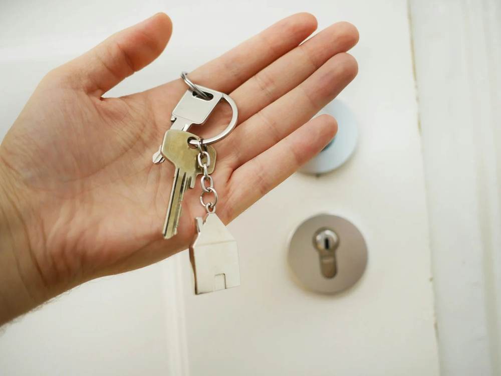 Hand holding house keys at a front door